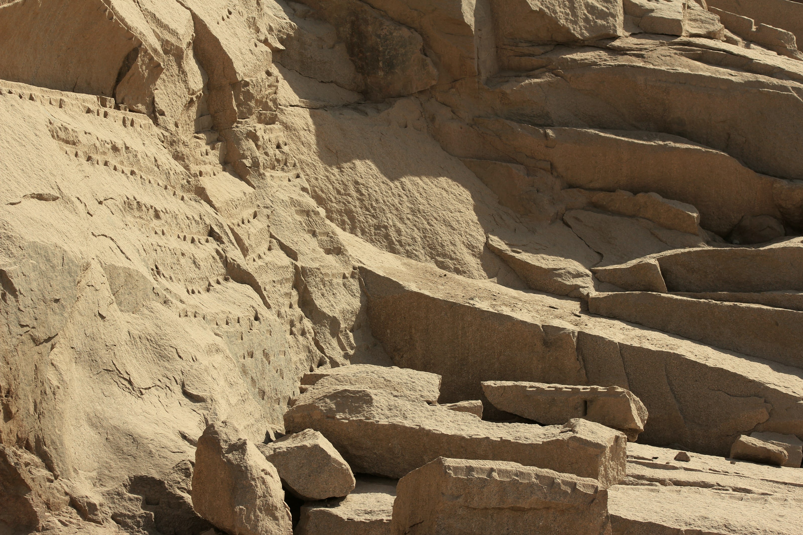 An Aswan granite quarry face with ancient tool marks and cut blocks in raking light — stone at its source.
